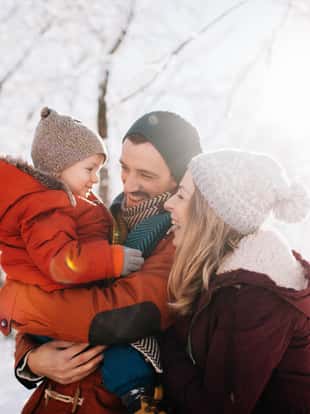 Photo of a cheerful young family, being playful outdoors in nature covered in snow