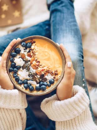 Pumpkin pie smoothie bowl topped with berries, granola, and coconut flakes