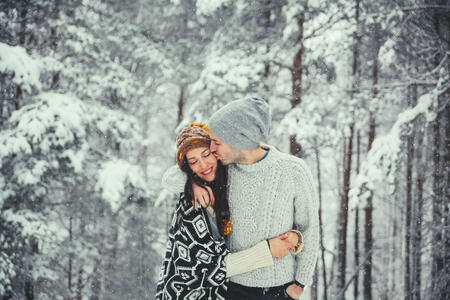 Young couple enjoying a trip to the mountain getaway for the weekend, walking, having fun in the woods covered in snow.