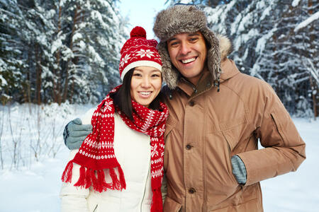 Happy young couple in winterwear looking at camera in natural environment
