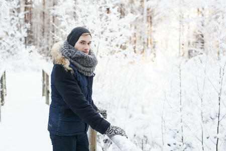 Portrait of young man taking a break in snowy forest to enjoy the view.