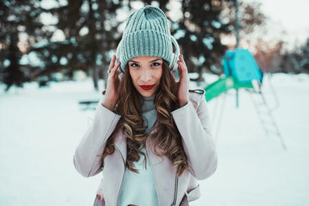 Young woman with headphones listening to music outdoors on a lovely winter day