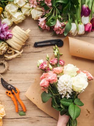 Partial view of florist making flower bouquet on wooden surface