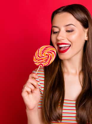 Close-up photo portrait of charming cute pretty dreamy lovely nice glad teenager, want to eat all the candies she has isolated bright background copy space