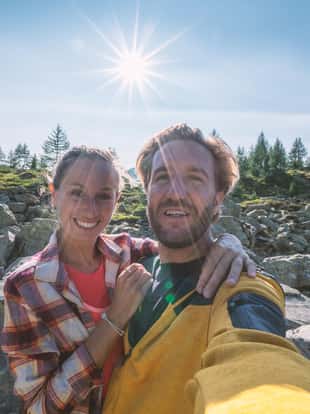 Cheerful young couple hiking Switzerland take a selfie on the mountain top. People travel concept.