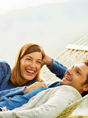 Happy mid adult couple relaxing on hammock outdoors