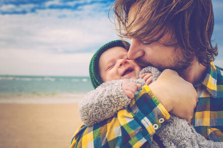 Happy father and his baby son having fun on the beach