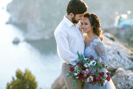 Newlyweds in beautiful clothes on the top of the mountain above the sea bay.