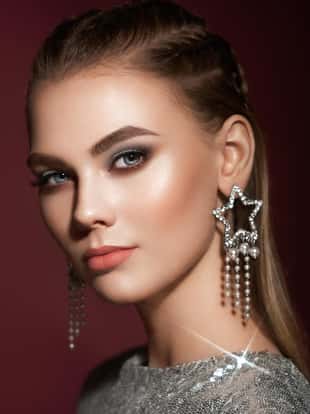 Portrait beautiful woman with jewelry. Brunette girl with long smooth hair. Beauty fashion. Eyelashes. Cosmetic eyeshadow. Care and beauty hair products. Model in a silver dress