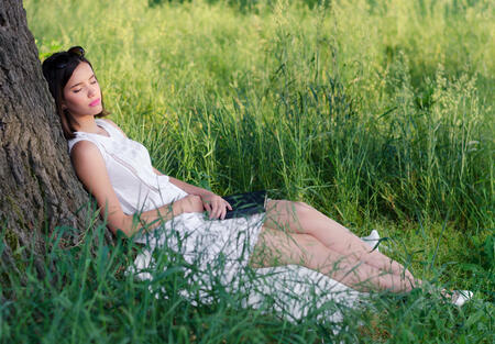 Beautiful woman sleeping in the nature after reading book on a sunny summer day.
