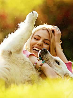 Young blonde woman is relaxing in the park with her retriever.