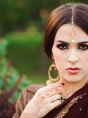 Portrait of beautiful indian girl. Young hindu woman model with tatoo mehndi and kundan jewelry. Traditional Indian costume saree.