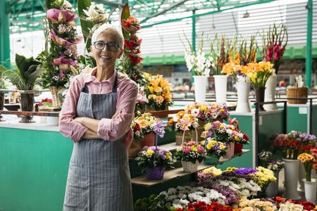 Portrait of charrming senior woman sales flowers on local market