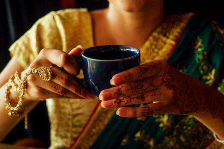 woman indian hold cup tea masala national smile.Female hands decoratively colored by henna with coffee mug