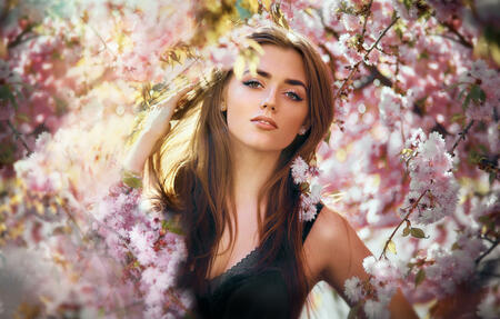 beautiful young woman in blooming cherry blossoms garden