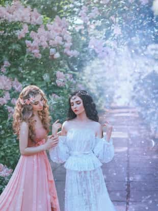 sexy portrait two women type spring and winter, perfect skin gentle makeup. Long curly hair brunette and blonde lady. Jewelry tiara wreath diadem. Vintage lace outfits. frozen flower garden snow