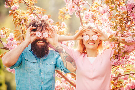 Smiling couple in love on blossoming tree garden background. Man Couple near sakura tree. Happy easter. Hunting Egg