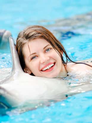 portrait of a young smiling girl in a pool with dolphins