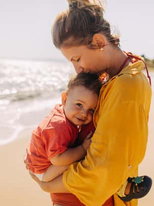 Photo of mother hugging her baby boy while enjoying together at the beach