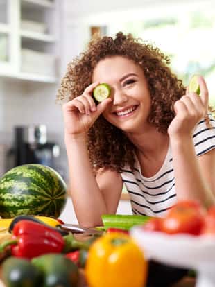 Woman holding a slice of cucumber