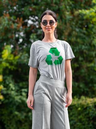 Young smiling attractive woman in gray t-shirt with recycle symbol in park. Eco symbol.