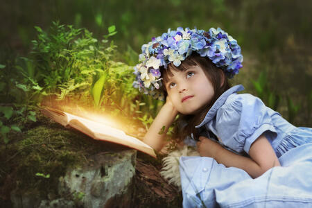 Reading fairy tales by a little girl in a meadow