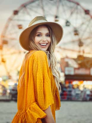 Beautiful exited smiling tourist woman having fun at amusement park at hot summer day trip on the beach in New York