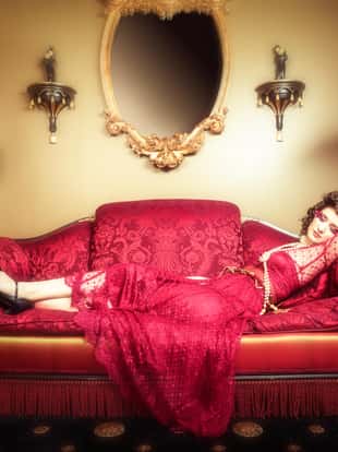 Beautifull woman lying down on victorian fainting couch.