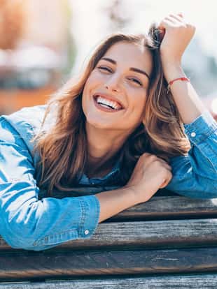 Beautiful young woman resting outdoors on a bench