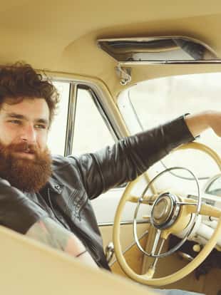 Man with beard driving a retro car