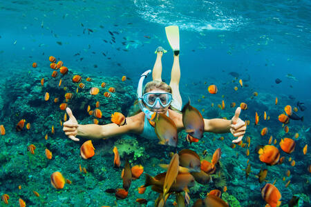 Happy family - girl in snorkeling mask dive underwater with tropical fishes in coral reef sea pool. Travel lifestyle, water sport outdoor adventure, swimming lessons on summer beach holiday with kids