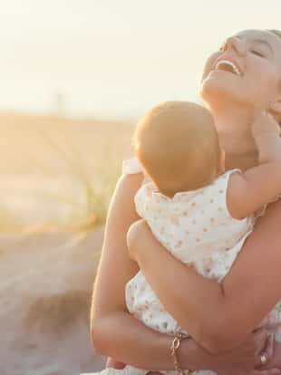 Shot of happy mother holding her baby girl on the beach.