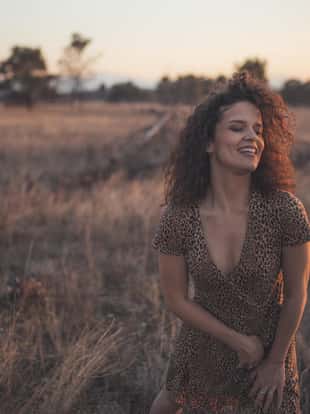 Curly hair woman posing in the jungle in her leopard dress