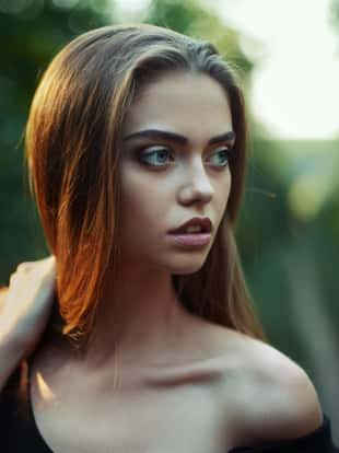 Portrait of beautiful young woman looks aside on the nature