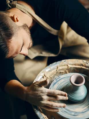 Potter modeling ceramic pot from clay on a potter's wheel. Workshop, art concept