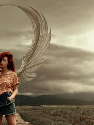 Redhead fantasy angel in the cornfield, posing on a stormy and apocalyptical background, wearing wings