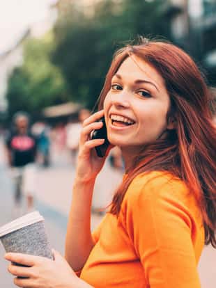 Beautiful happy woman talking on the phone outside in the city.