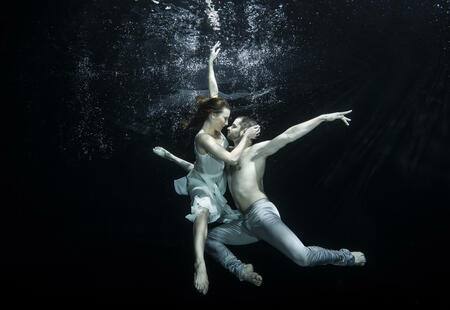 Yong couple of ballet dancers dacing underwater