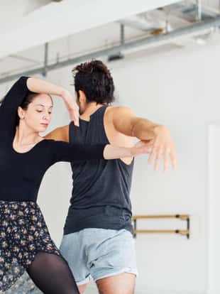 Young man and woman rehearsing ballet dance. Low angle view of male and female dancers are performing at studio. They are wearing sportswear.