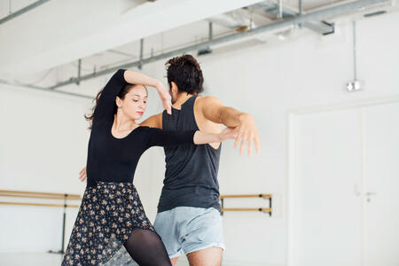 Young man and woman rehearsing ballet dance. Low angle view of male and female dancers are performing at studio. They are wearing sportswear.