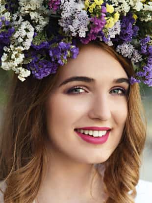Smiling young woman wearing crown made of flowers