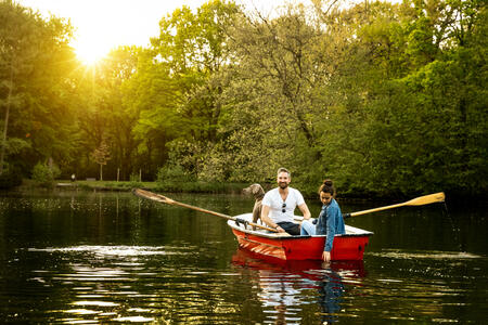Father, daughter and Weimaraner dog in rowboat on lake