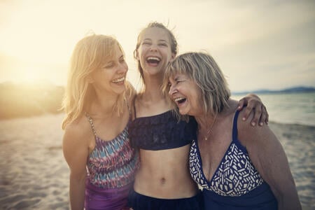 Three generations - Grandmother, mother and daughter enjoying time together on the beach. Women are laughing happily and embracing. Nikon D850