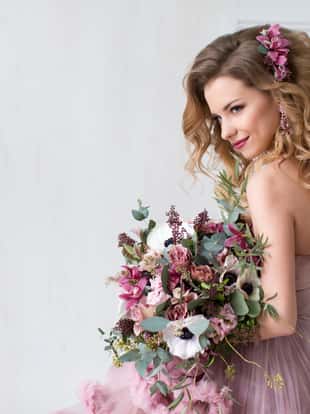 Young Happy Bride With Flower Bouquet in pink dress. beauty and fashion.