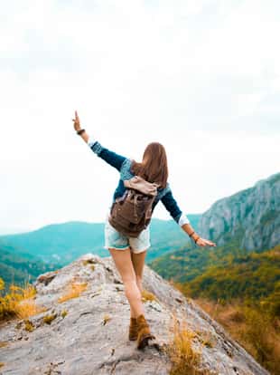 Young Hippie girl taking a walk on top of a mountain and enjoying the day. rear view