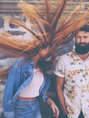 Retro style image hipster guy standing next to a hipster girl flinging her red hair wildly