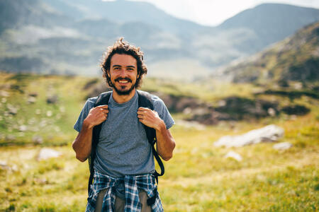Happy male hiker standing in the beautiful mountain.