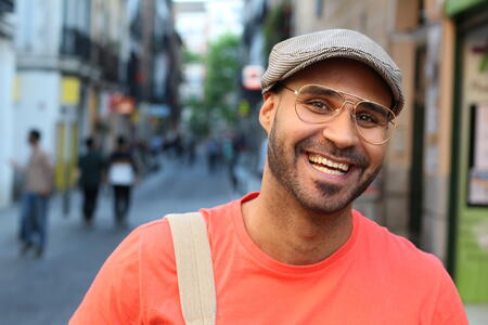 Retro styled ethnic man smiling outdoors.