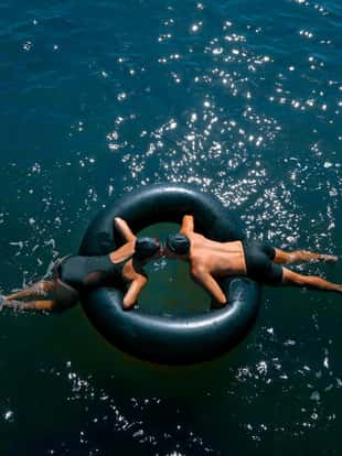 couple kissings while floating on inner tube in ocean