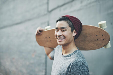 Shot of a young man holding a skateboard outside